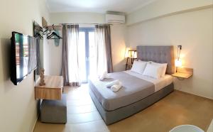 1 dormitorio con 1 cama y TV en CELENI APARTMENTS en Lefkada