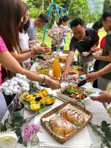 Jing Lai Hui Lan Homestay في رويسي: مجموعة من الناس تقف حول طاولة مع الطعام