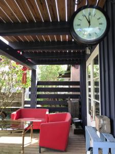 een klok op een patio met rode stoelen en een tafel bij Cardinalis house in Pāvilosta