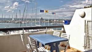 un tavolo blu e sedie su un balcone con porto turistico di Rivages d'Ulysse Port Camargue a Le Grau-du-Roi