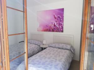 dwa łóżka w pokoju z obrazem na ścianie w obiekcie Casa Carminuca w mieście Ayuela