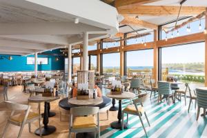 a restaurant with tables and chairs and large windows at Oystercatcher Apartments in Polzeath