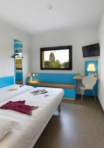 a room with two beds and a desk and a window at First Inn Hotel Blois in Blois