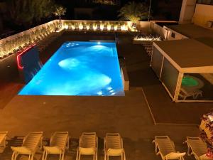 una piscina notturna con sedie intorno di Hotel Milanese a Rimini