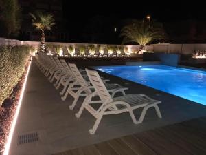 a row of chairs next to a swimming pool at night at Hotel Milanese in Rimini