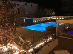 a backyard with a swimming pool at night at Hotel Milanese in Rimini