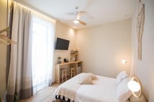 a white bedroom with a bed and a window at Ederlezi Boutique Hotel in Athens