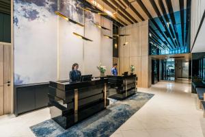 曼谷的住宿－The Key Premier Hotel Sukhumvit Bangkok，两个人站在大堂的桌子旁