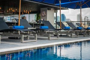 a row of lounge chairs next to a swimming pool at The Key Premier Hotel Sukhumvit Bangkok in Bangkok