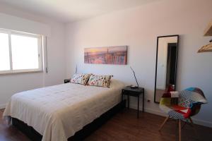 um quarto com uma cama, uma cadeira e uma janela em House Beach em Costa da Caparica