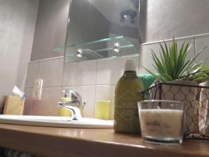 a bathroom sink with a bottle of soap and a glass at LA GRENOUILLERE gîte 3 chambres in Frévin-Capelle