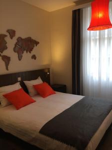 a bedroom with a bed with red pillows and a red lamp at B&B Geste d' Alice in Middelkerke