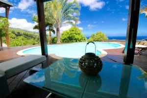 a glass table in front of a swimming pool at KAZ ORÈA in Saint-Leu