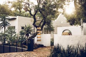 Una casa blanca con un árbol delante. en Bly B&B en Pretoria