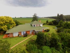 une vue aérienne sur une maison avec un toit vert dans l'établissement Little Acres Drakensberg Accommodation, à Champagne Valley