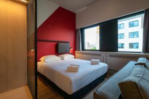 a bedroom with a large bed and a red wall at Via Suites in Amsterdam