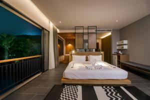 奈汉海滩The Gallery Hotel Nai Harn的一间带大床的卧室和一个阳台