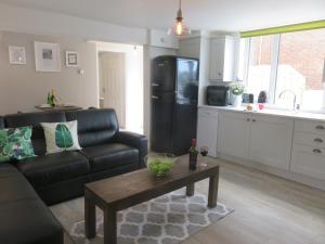 a living room with a black couch and a table at Esk Cottage - Cyanacottages in Whitby