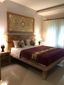 a bedroom with a large bed with a wooden headboard at Betutu Bali Villas in Ubud