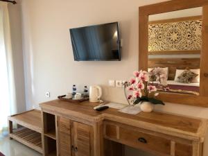 a room with a wooden table with a tv on the wall at Betutu Bali Villas in Ubud