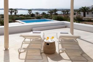 een patio met 2 stoelen, een tafel en een zwembad bij The Sand Collection Villas in Santa Maria