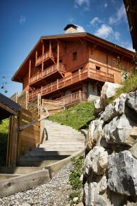 ein großes Holzgebäude mit einer Treppe, die dorthin führt in der Unterkunft CGH Résidences & Spas les Chalets du Soleil Authentiques in Les Menuires