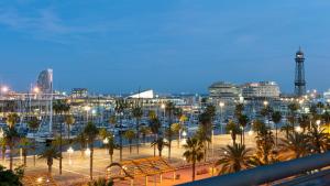 a marina with palm trees and a city at night at Duquesa de Cardona Hotel 4 Sup by Duquessa Hotel Collection in Barcelona