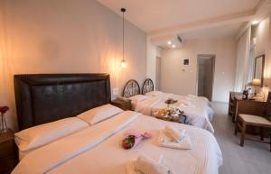 a bedroom with two beds with white sheets and flowers at Filoxenia Hotel in Volos