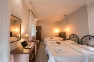 a hotel room with three beds and a laptop on a desk at Filoxenia Hotel in Volos