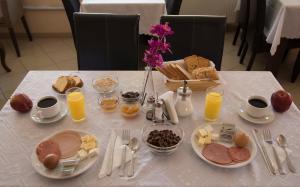 a table topped with breakfast foods and orange juice at Filoxenia Hotel in Volos