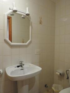 La salle de bains est pourvue d'un lavabo, d'un miroir et de toilettes. dans l'établissement Apartamentos Jardin Playa, à Punta Grossa