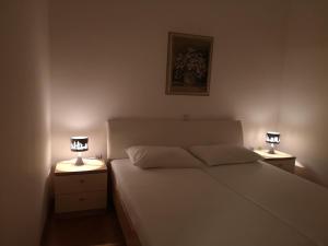 a bedroom with a white bed and two night stands with lamps at Spacious apartment on a great location -Apartment Kuhta in Biograd na Moru