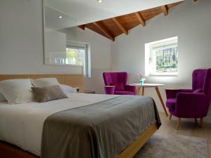 um quarto com uma cama e 2 cadeiras roxas em Hotel Nande em Nieves