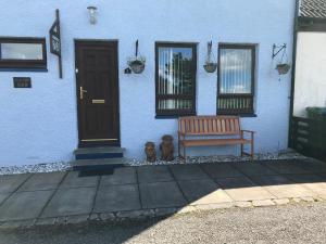 Dois ursos de peluche sentados ao lado de um banco em frente a uma casa. em Creag Dubh Bed & Breakfast em Kyle of Lochalsh