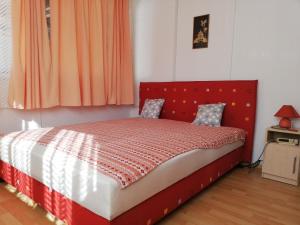 een bed met een rood hoofdeinde in een slaapkamer bij Bartók Apartmanház in Balatonszárszó