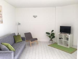 een woonkamer met een bank en een tv bij Esquina do Mar in Armação de Pêra