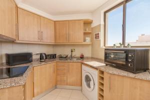 een keuken met een magnetron, een wasmachine en een droger bij Esquina do Mar in Armação de Pêra