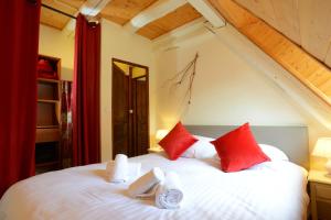 ein Schlafzimmer mit einem großen weißen Bett mit roten Kissen in der Unterkunft RIBEAUVILLE city center - Gîte des Ménétriers, LES VIEILLES VIGNES - in Ribeauvillé