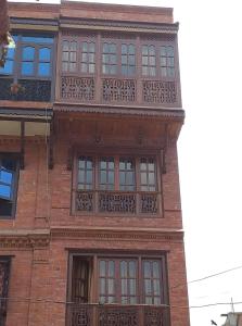 a tall brick building with a balcony on it at Pottery Home in Bhaktapur