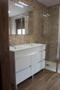 een badkamer met een witte wastafel en een spiegel bij LA VILLA DE FON in Fuentes de Carbajal