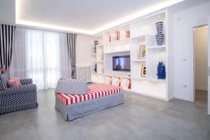 een woonkamer met een bank, stoelen en een televisie bij YourHome - Unica Luxury Apartment in Castellammare di Stabia
