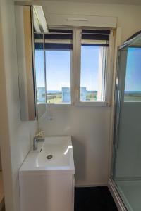 a bathroom with a sink and a mirror and two windows at La maison des gardiens de l'Océan & spa - Les Gîte de Fabie - Plougonvelin in Plougonvelin