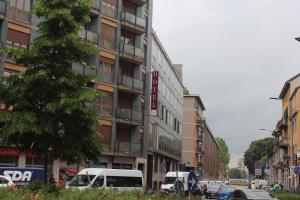 una calle de la ciudad con coches aparcados frente a un edificio en Hotel Giacosa en Milán