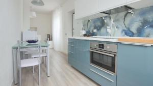 eine Küche mit blauen Schränken und einem Glastisch in der Unterkunft La Terrazza di Casarico in Moltrasio