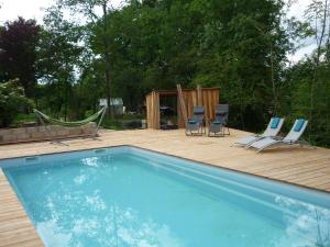 a swimming pool with chairs and a wooden deck at Hexagonal Tower for 2 with shared pool in Semur-en-Auxois