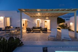 a patio with chairs and a pergola at night at The Sand Collection Villas in Santa Maria