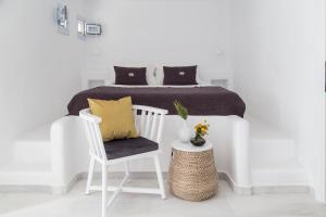 a white bedroom with a bed and a chair at The Sand Collection Villas in Santa Maria