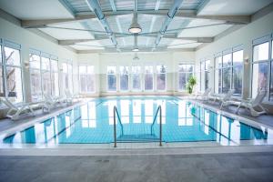 a swimming pool with chairs and windows at Vitalhotel Weisse Elster in Bad Elster