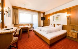 a hotel room with a large bed and a desk at Tanneck Garni in Berwang