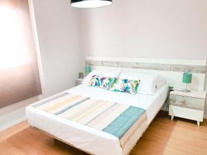 a white bedroom with a bed with two pillows at Paseo de La Victoria in Córdoba